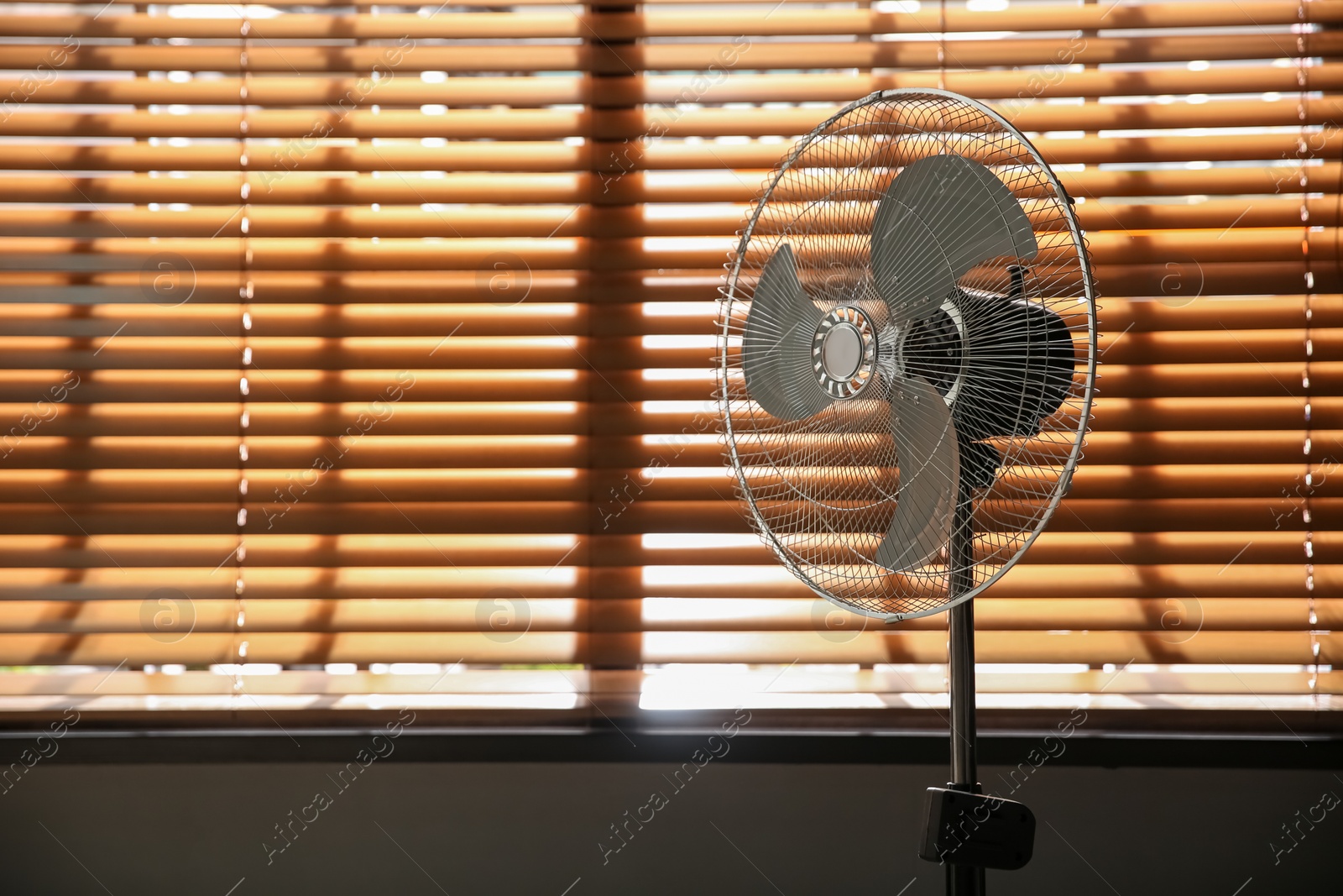 Photo of Modern electric fan near window indoors. Space for text