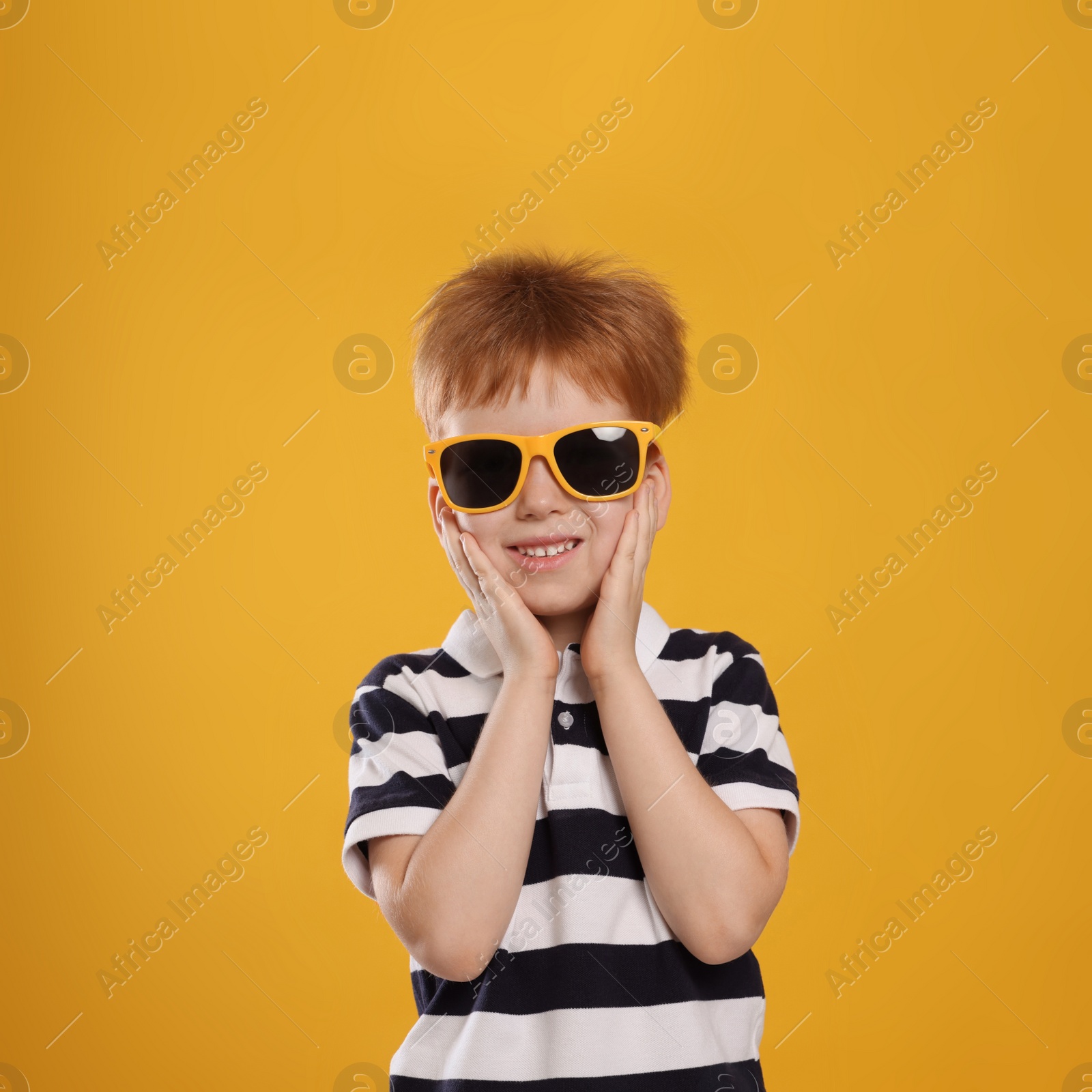 Photo of Cute little boy with sunglasses on yellow background