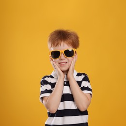 Photo of Cute little boy with sunglasses on yellow background