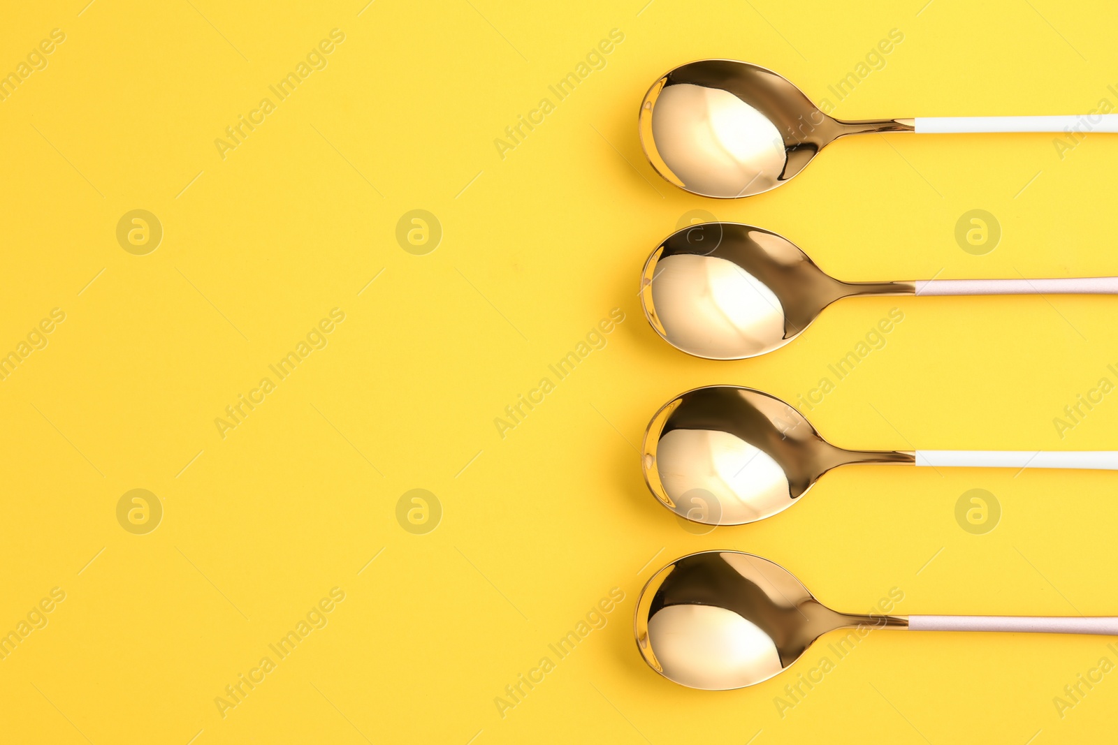 Photo of Flat lay composition with clean tablespoons and space for text on color background