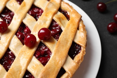 Delicious pie with cherries on black table, closeup