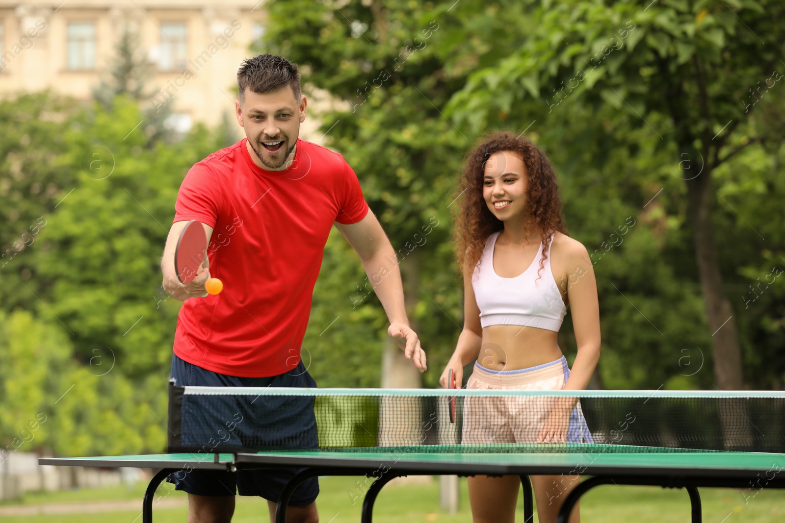 Photo of Friends playing ping pong outdoors on summer day