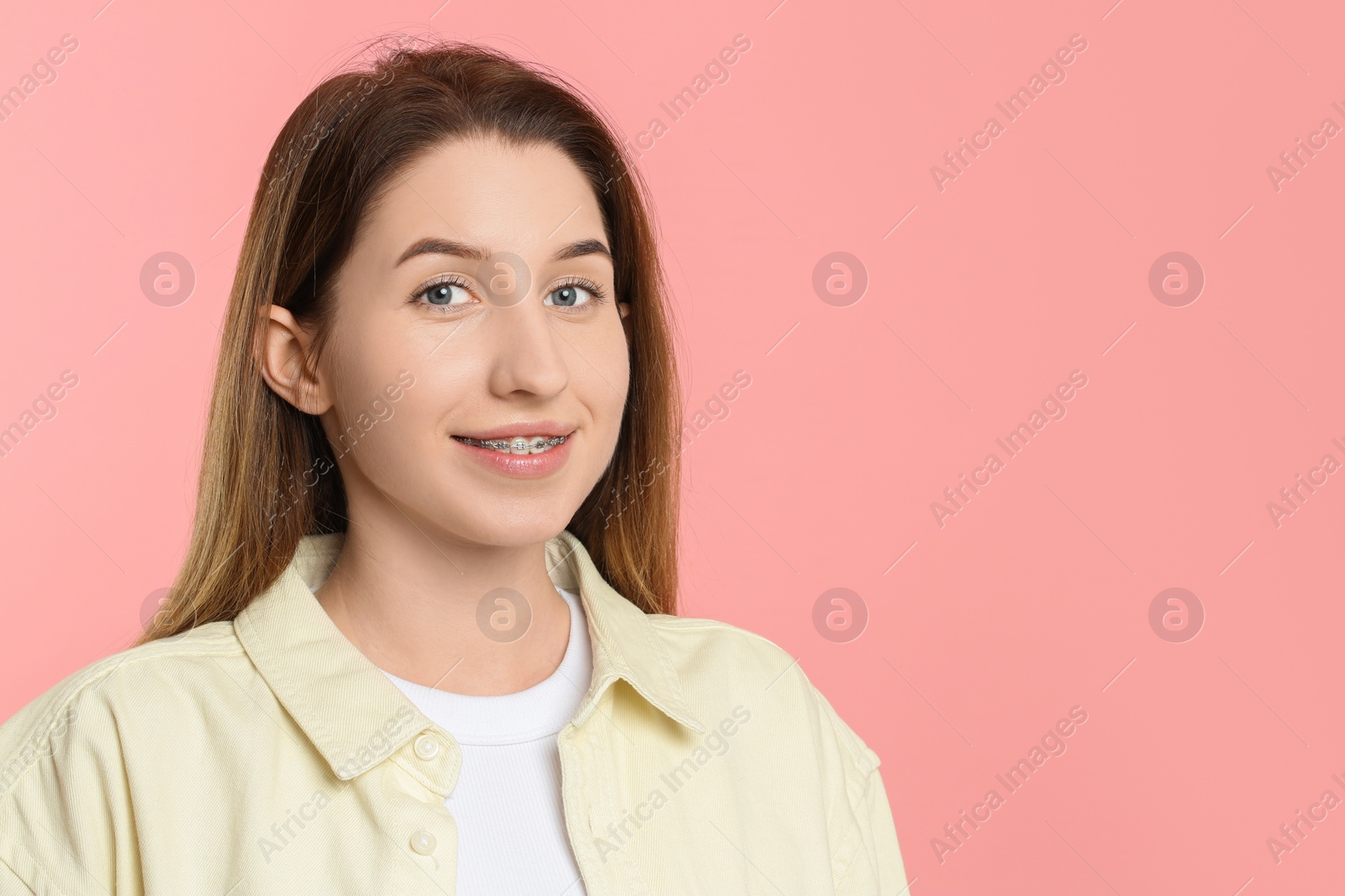 Photo of Portrait of smiling woman with dental braces on pink background. Space for text