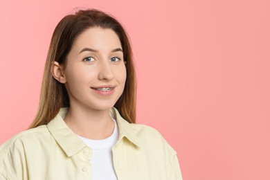 Portrait of smiling woman with dental braces on pink background. Space for text