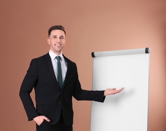 Photo of Young business trainer near flip chart on color background