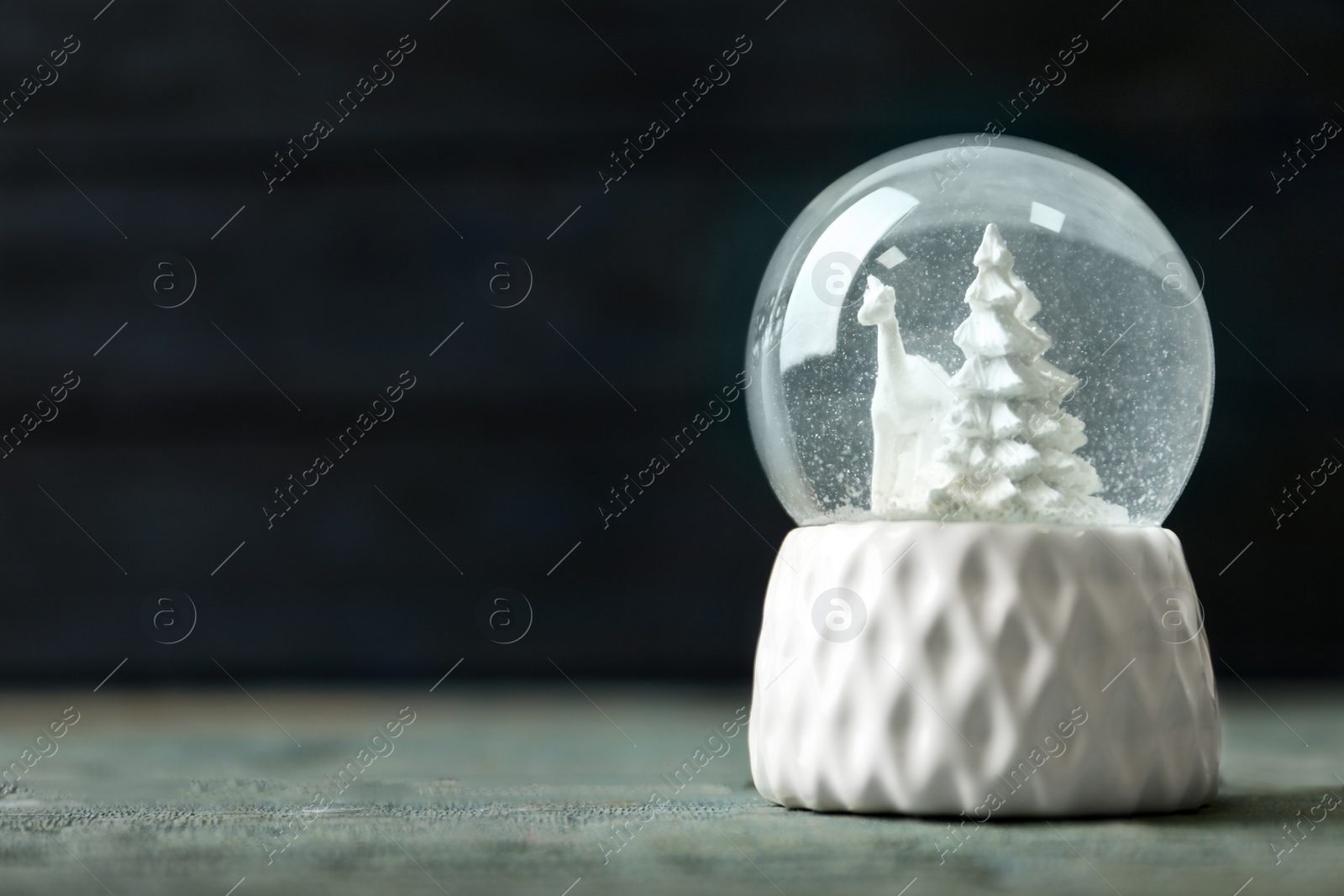 Photo of Snow globe with deer and trees on blue wooden table, space for text. Christmas season