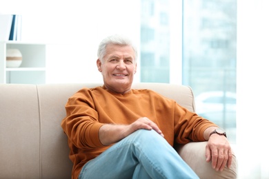 Portrait of handsome mature man on sofa indoors