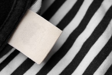 Photo of Clothing label on striped garment, top view. Space for text