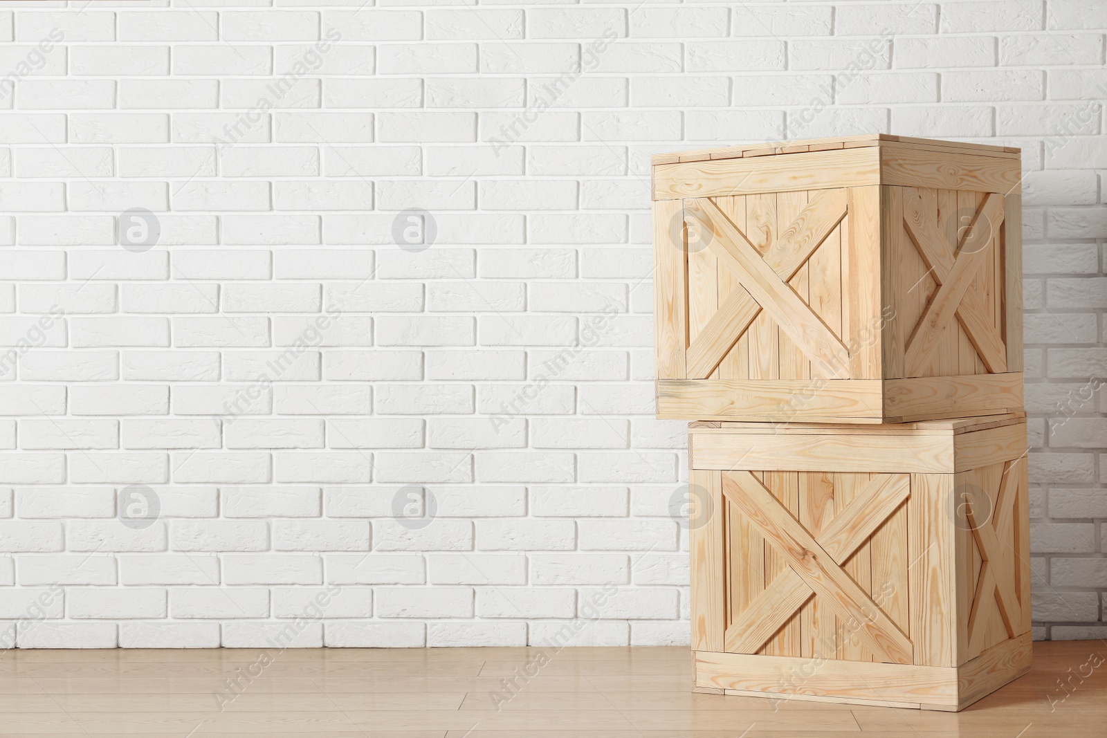 Photo of Wooden crates on floor near brick wall, space for text