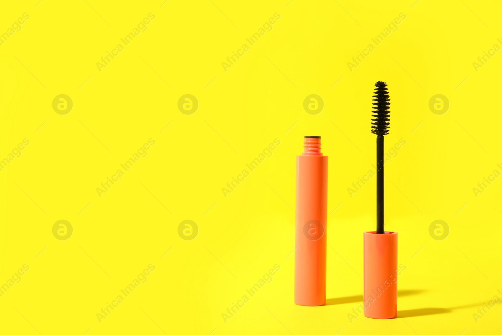 Photo of Mascara on yellow background, space for text. Makeup product