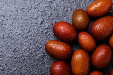 Photo of Heap of ripe red dates with water drops on grey table, top view. Space for text