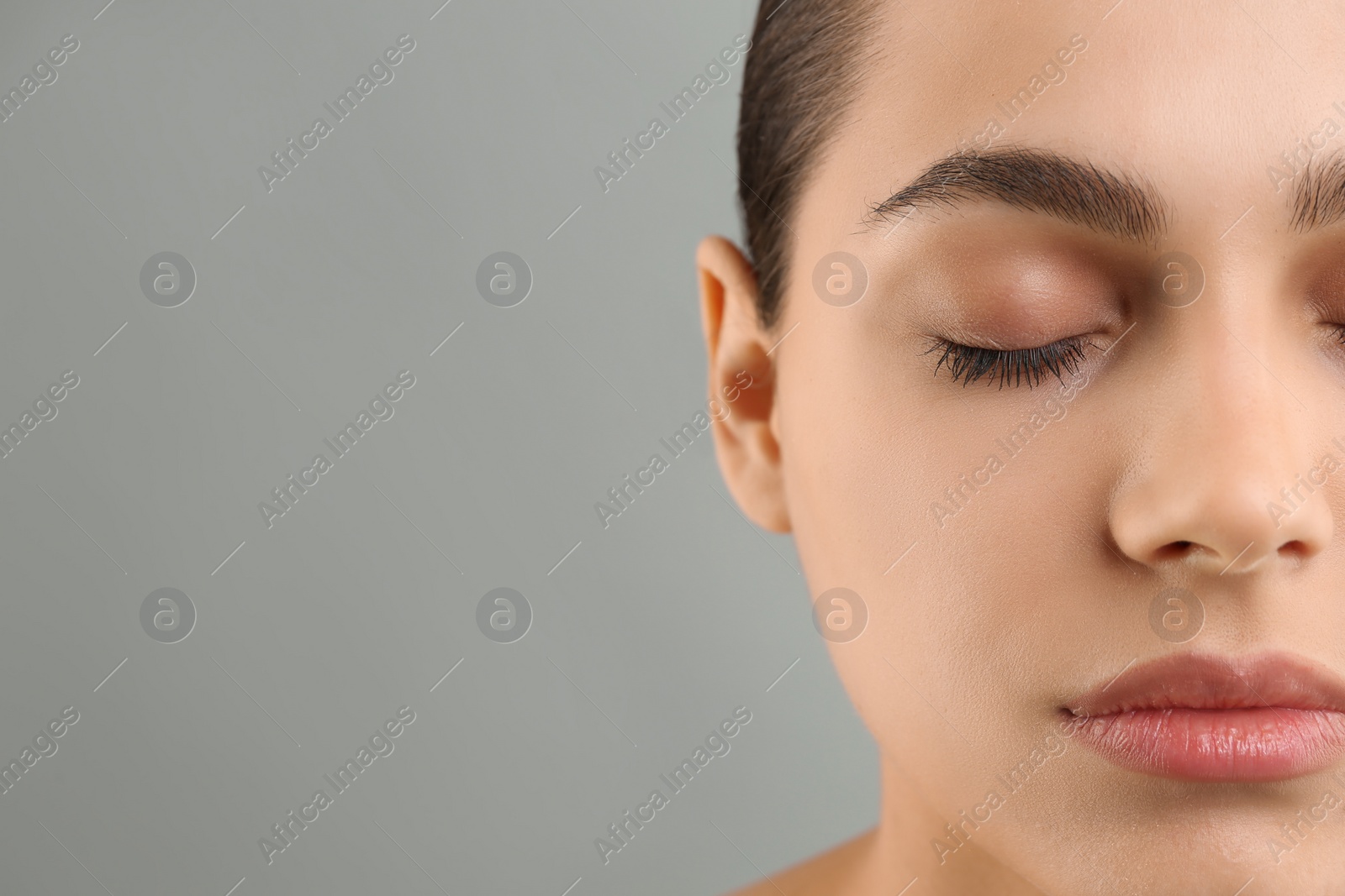 Photo of Young woman with perfect eyebrows on grey background, closeup. Space for text