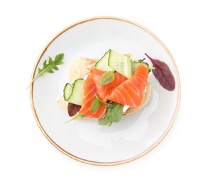 Tasty bruschetta with salmon, cucumbers and herbs on white background, top view