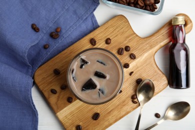 Photo of Glass of milk with grass jelly and coffee beans on white wooden table, flat lay