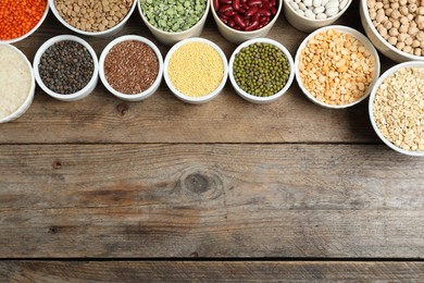 Photo of Different grains and cereals on wooden table, flat lay. Space for text