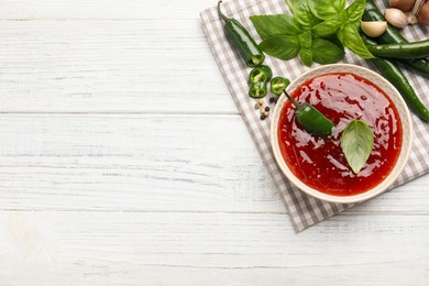 Photo of Spicy chili sauce and ingredients on white wooden table, top view. Space for text