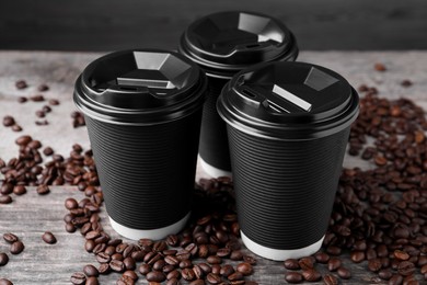 Photo of Coffee to go. Paper cups and roasted beans on wooden table, closeup