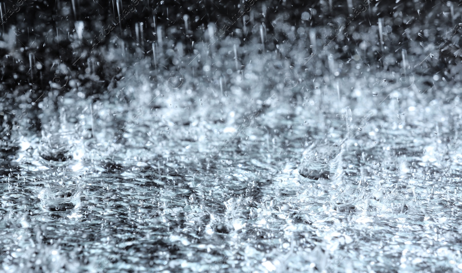 Photo of Heavy rain falling down on ground against dark background