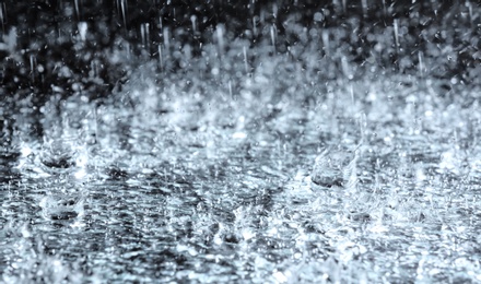 Photo of Heavy rain falling down on ground against dark background