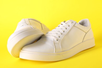 Photo of Pair of stylish white sneakers on yellow background