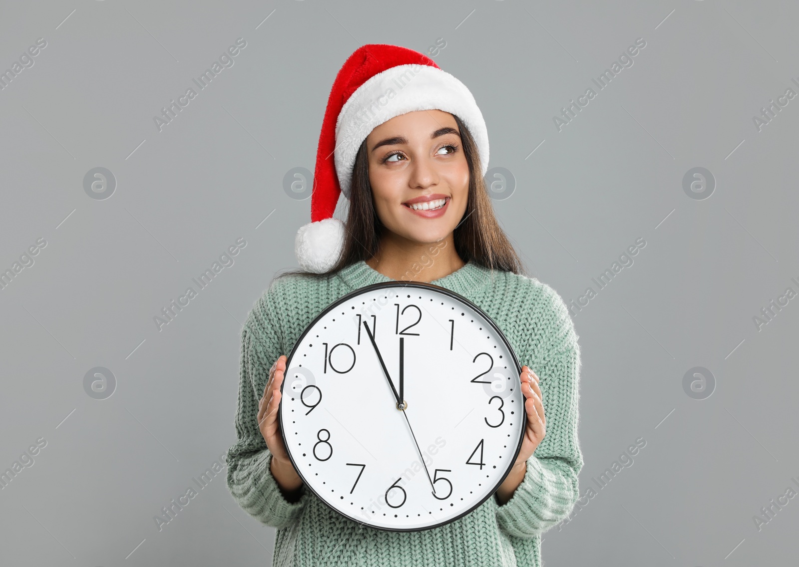 Photo of Woman in Santa hat with clock on grey background. New Year countdown