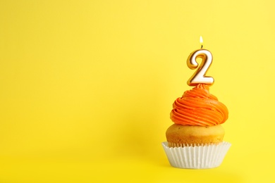 Photo of Birthday cupcake with number two candle on yellow background, space for text