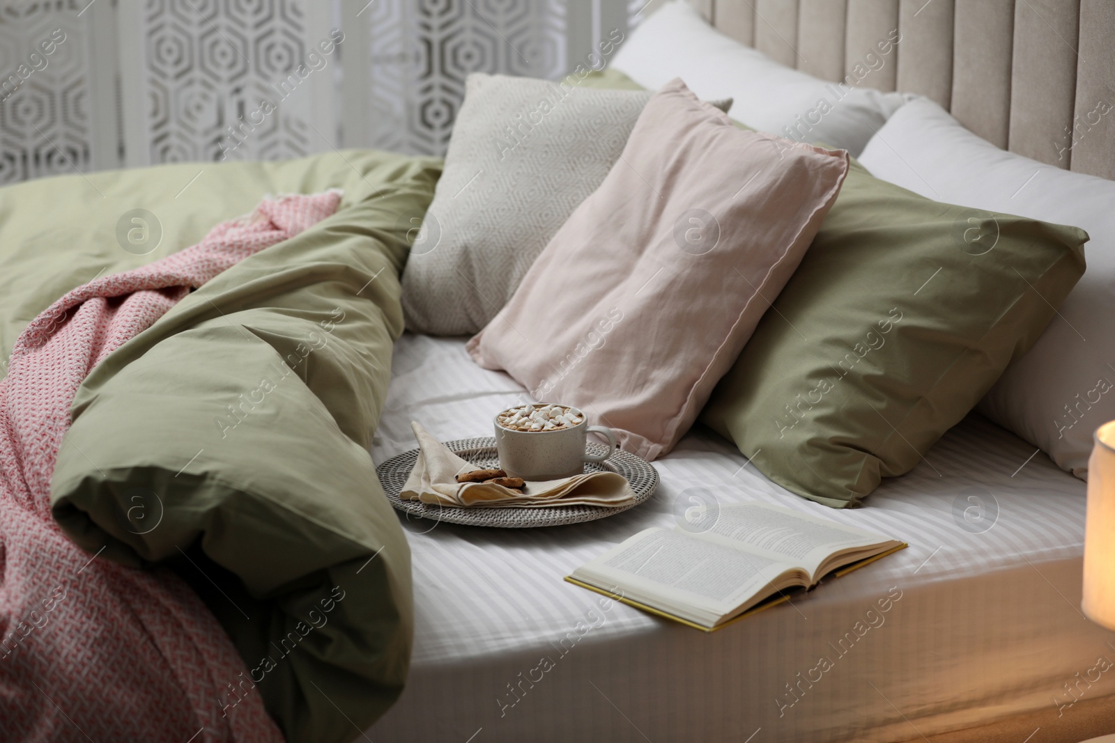 Photo of Cup of drink, cookies and book on bed with new pistachio linens