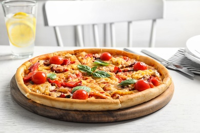 Photo of Delicious pizza with tomatoes and sausages on table