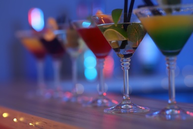 Different martini cocktails on table against blurred background, closeup with space for text