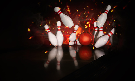 Image of Bowling ball bouncing pins with fire. Successful hit - strike