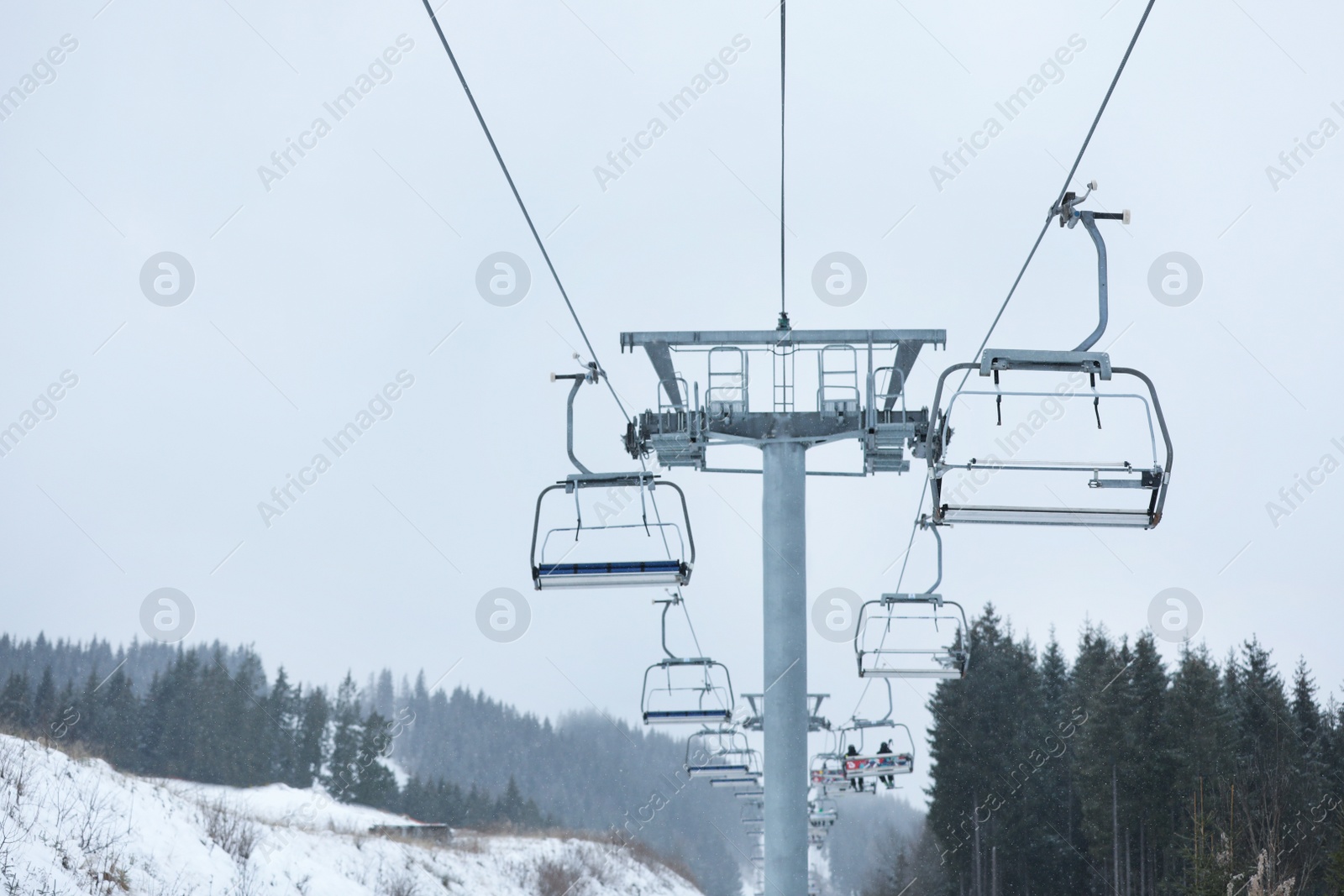 Photo of Chairlift with people at ski resort. Winter vacation