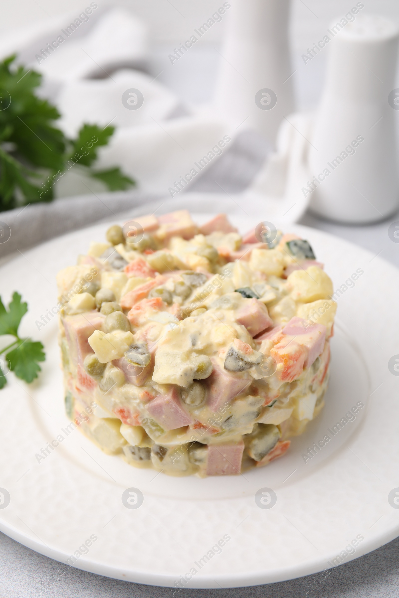Photo of Tasty Olivier salad with boiled sausage on white table, closeup