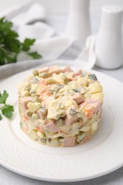 Tasty Olivier salad with boiled sausage on white table, closeup