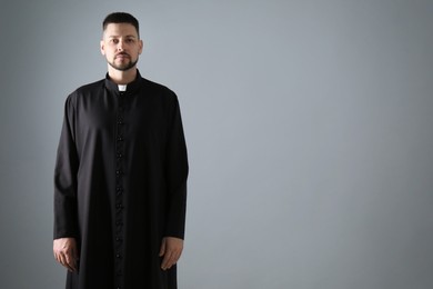 Photo of Priest wearing cassock with clerical collar on grey background, space for text