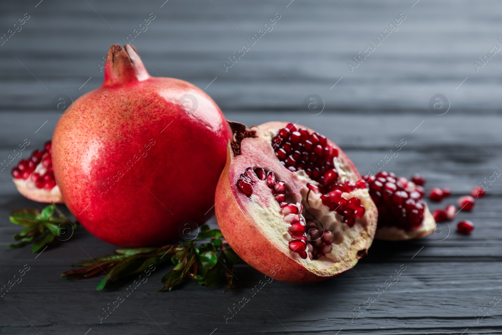 Photo of Delicious ripe pomegranates on grey wooden table