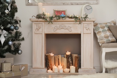 Decorative fireplace and Christmas tree with gift boxes in stylish living room interior