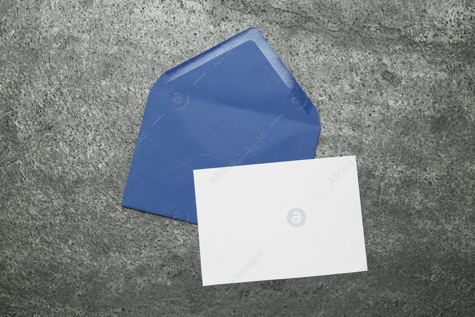 Photo of Envelope with blank paper card on grey table, top view