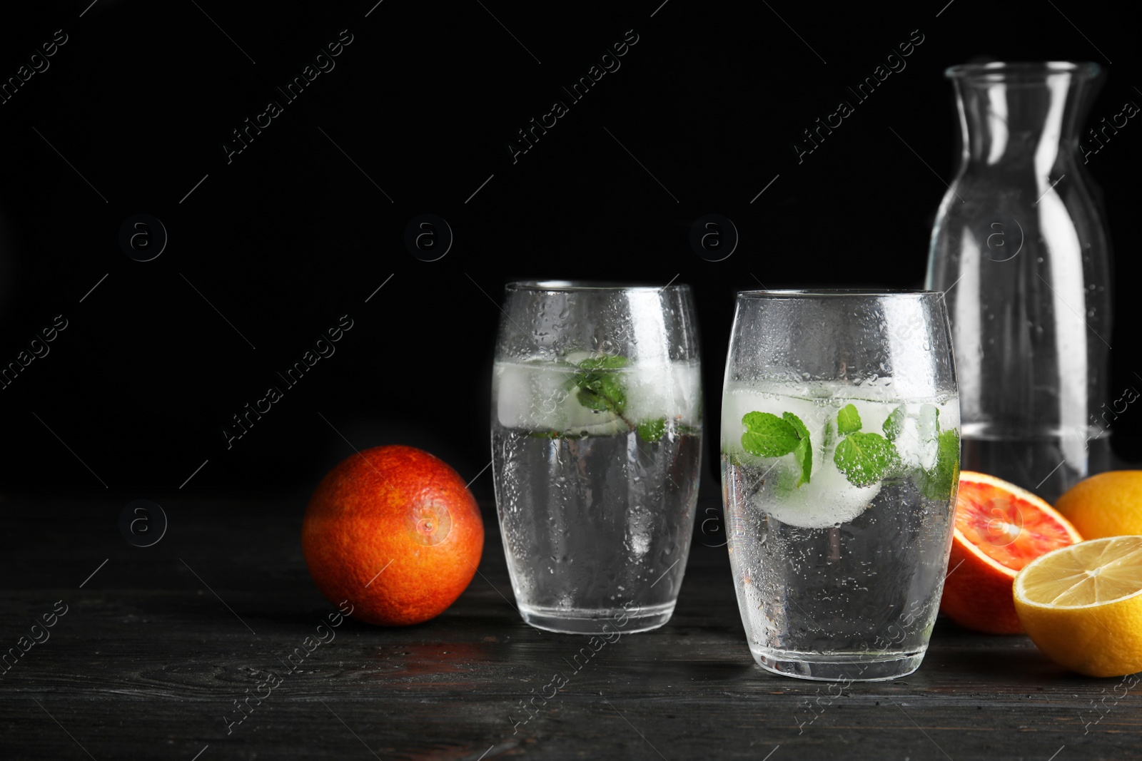 Photo of Composition with refreshing drink with mint and ice cubes in glasses on dark table. Space for text