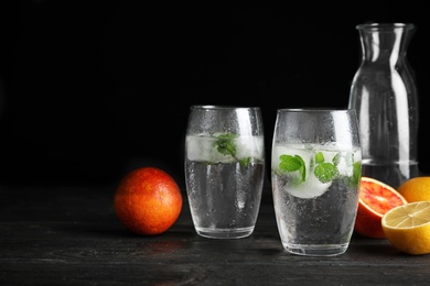 Photo of Composition with refreshing drink with mint and ice cubes in glasses on dark table. Space for text