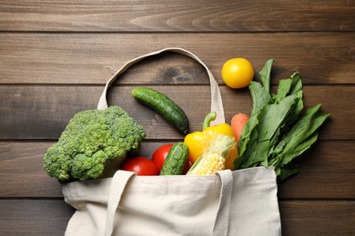 Photo of Cloth bag with different vegetables on wooden table, flat lay