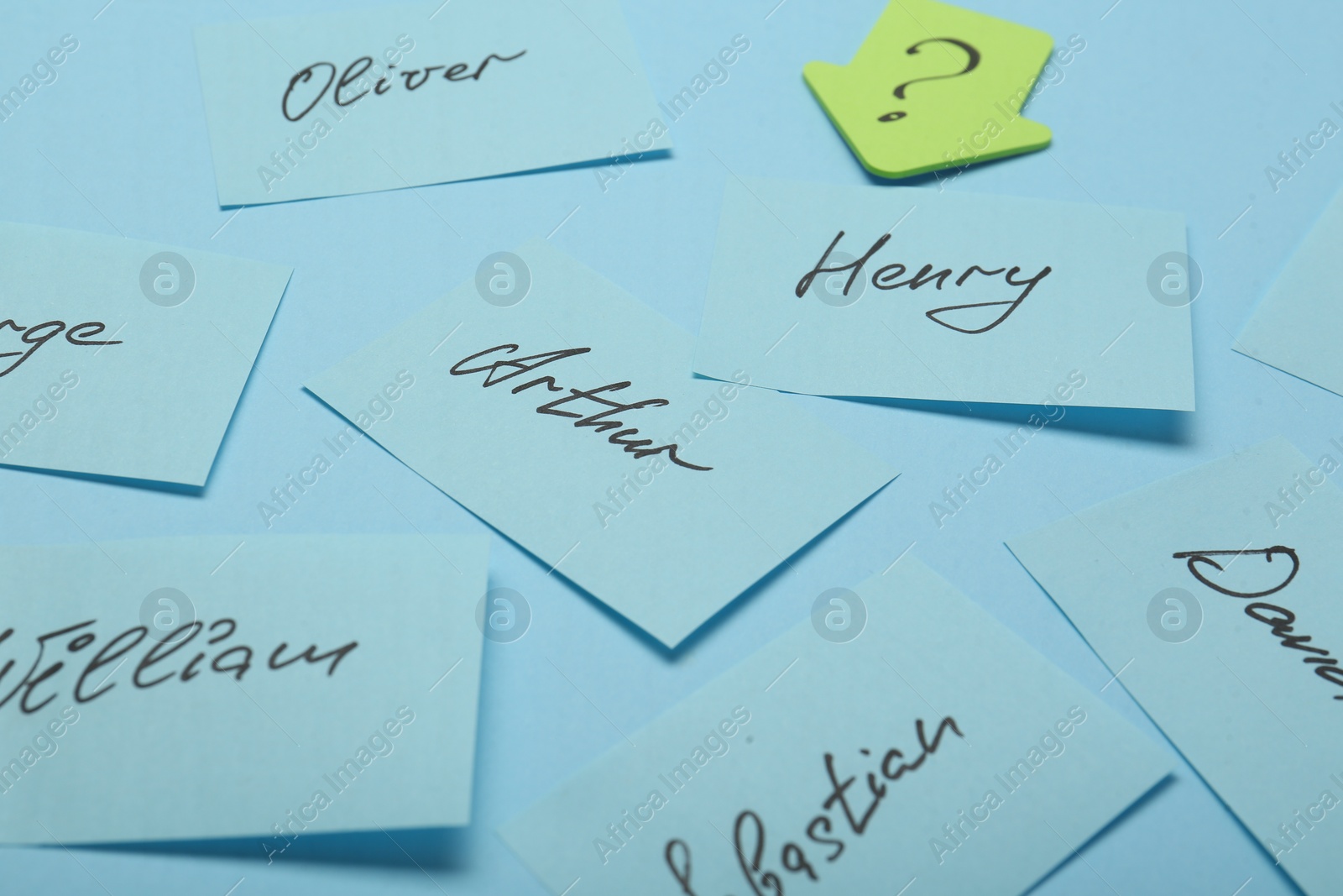 Photo of Choosing baby name. Paper stickers with different names and question mark on light blue background