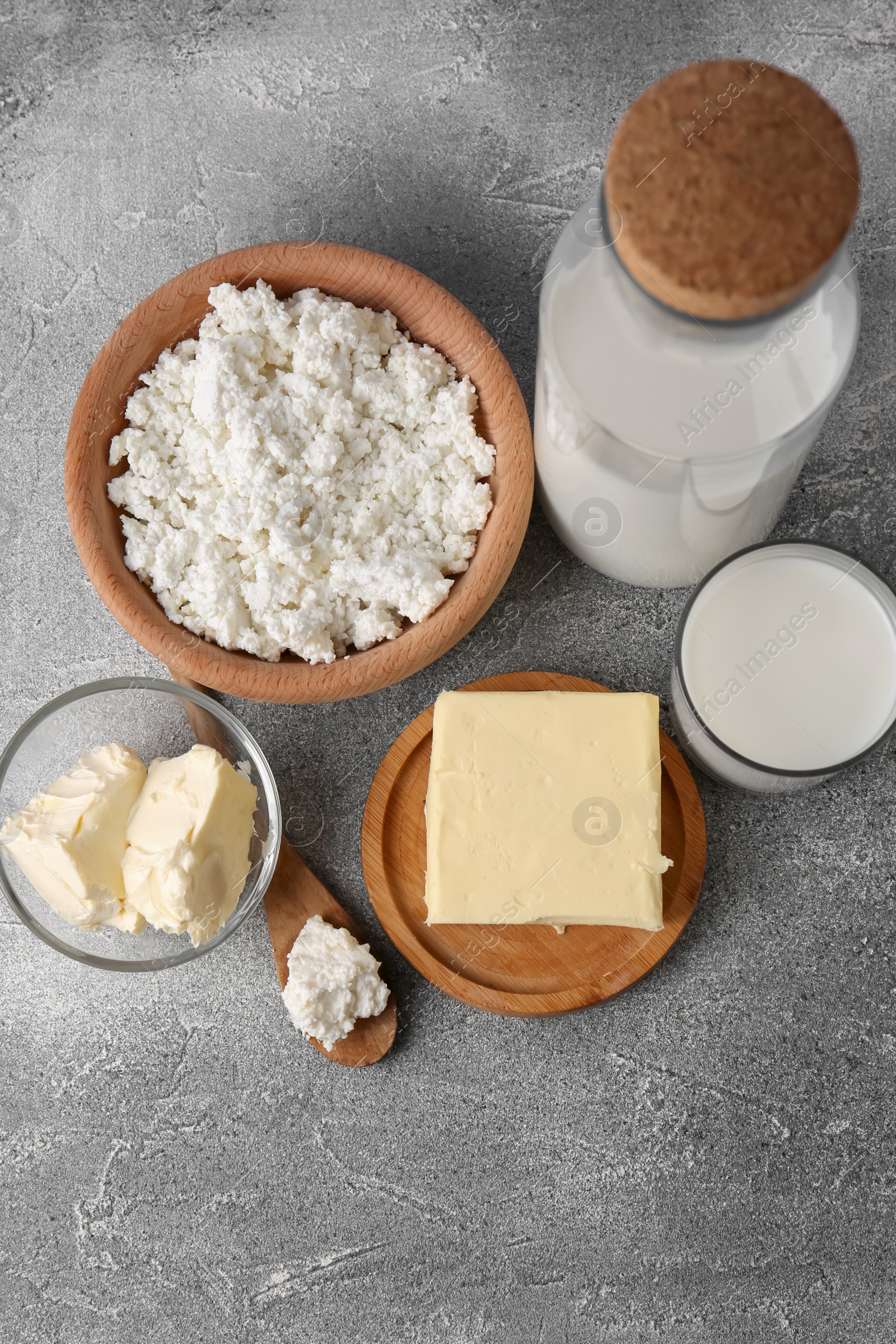 Photo of Tasty homemade butter and dairy products on grey table, flat lay