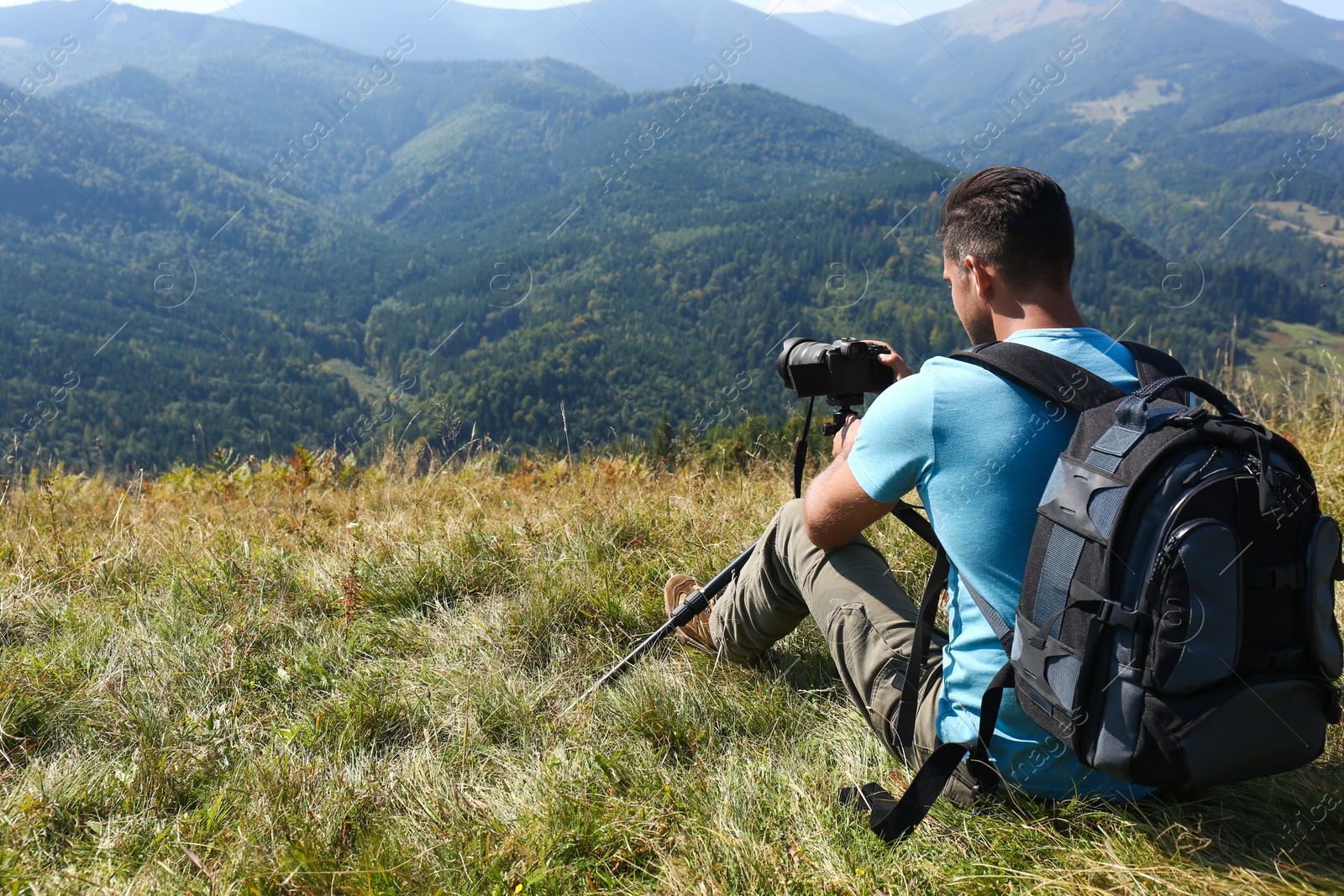 Photo of Photographer with backpack, camera and tripod surrounded by breathtakingly beautiful nature