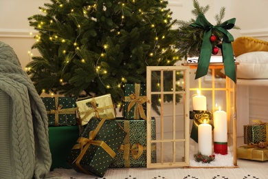 Photo of Wooden decorative lantern with burning candles near Christmas tree in room