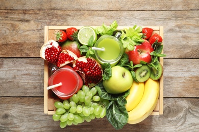 Photo of Wooden crate with juices in mason jars and fresh fruits on wooden background. Top view