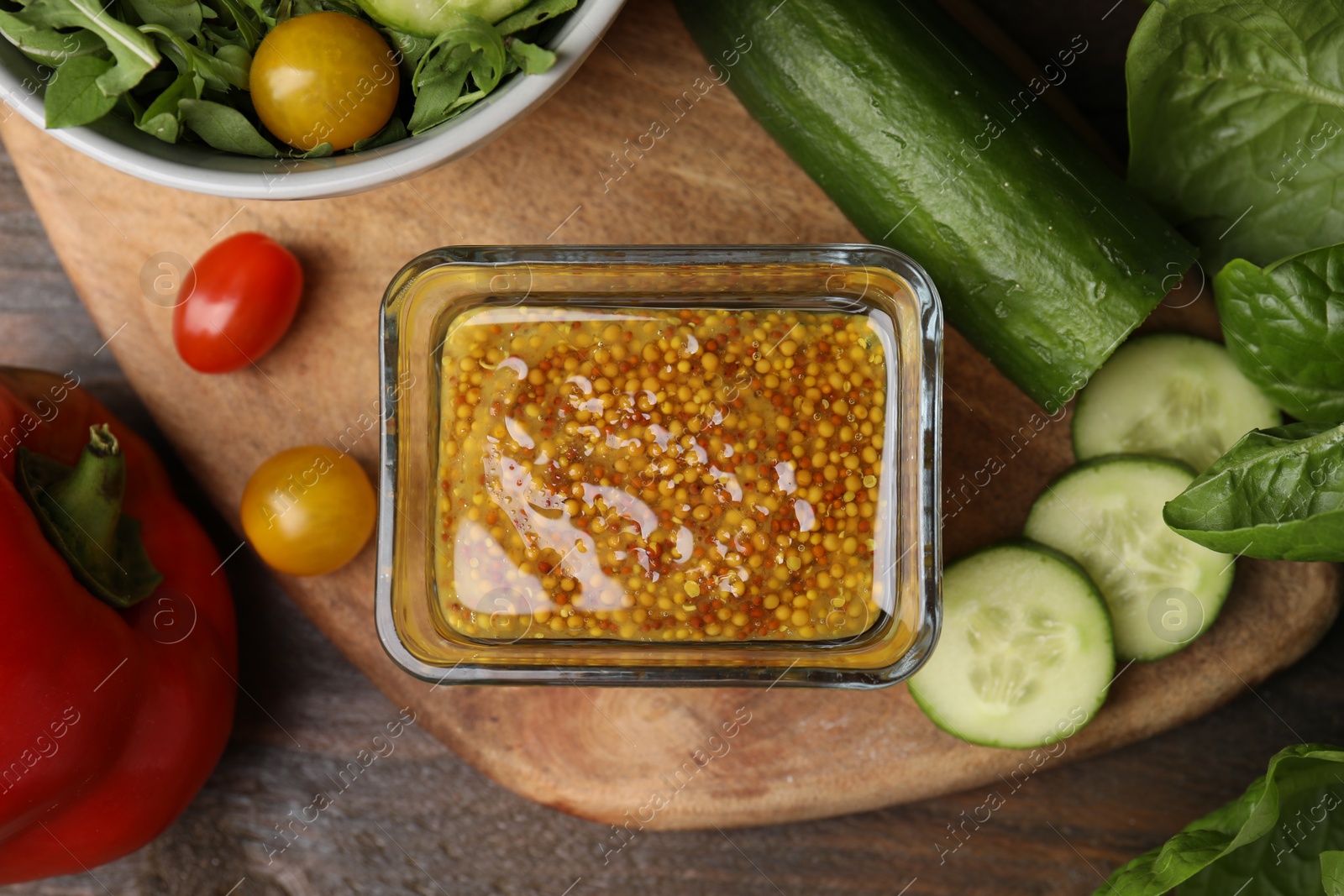 Photo of Tasty vinegar based sauce (Vinaigrette) in bowl and products on wooden table, flat lay