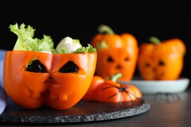 Photo of Bell pepper with black olives, mozzarella and lettuce as Halloween monster on dark table, closeup. Space for text