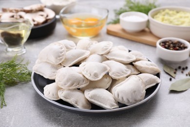 Photo of Raw dumplings (varenyky) and ingredients on grey table