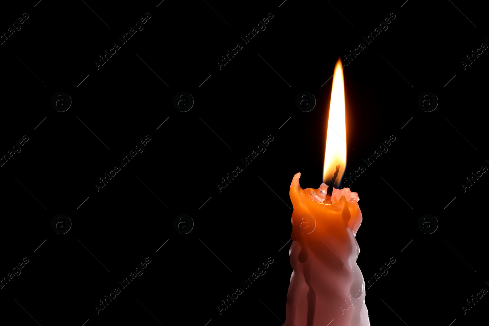 Photo of Burning candle on black background, closeup. Space for text