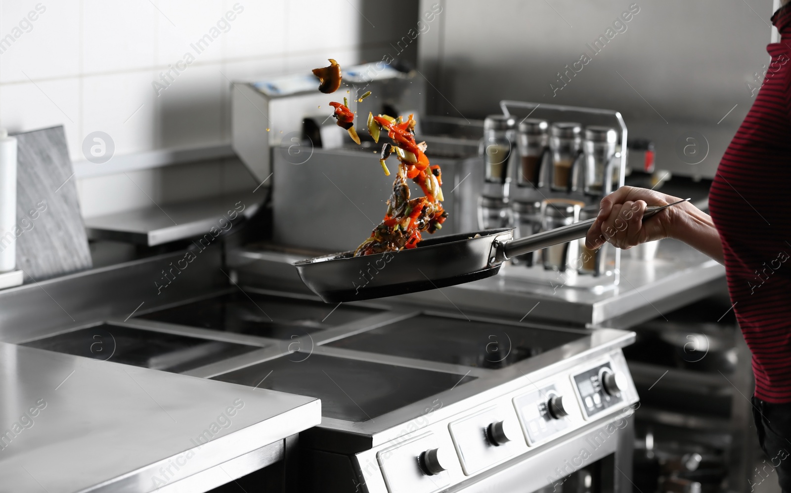 Photo of Woman cooking tasty food on stove in restaurant  kitchen, closeup